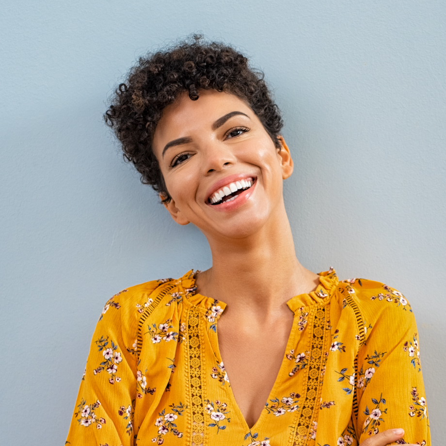 A portrait of a smiling woman in a yellow top.